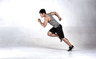 Athletic man sprinting in studio with white background