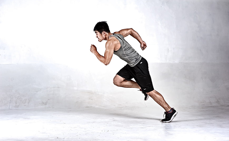 Athletic man sprinting in studio with white background