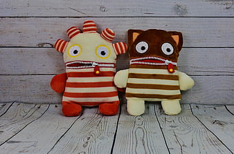 Two Cute Striped Worry Eater Plush Toys on Rustic White Wood