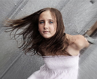 Portrait of young girl with windblown hair looking up