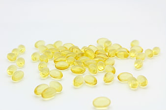 Yellow fish oil capsules scattered on white background