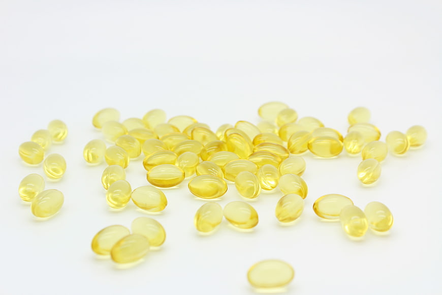 Yellow fish oil capsules scattered on white background