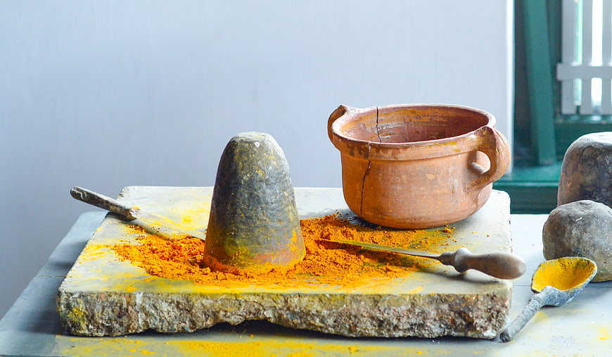 Traditional stone grinding slab with turmeric powder and clay pot