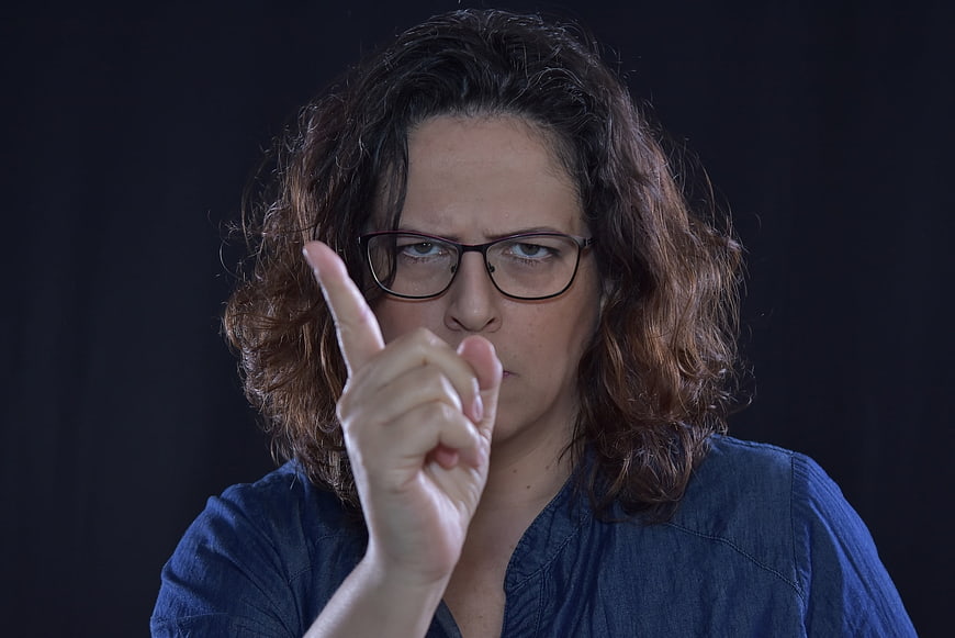 Angry woman with glasses pointing finger warning