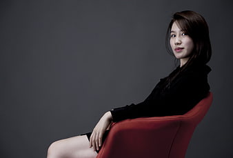 Studio Portrait of Woman in Black Seated on Red Chair