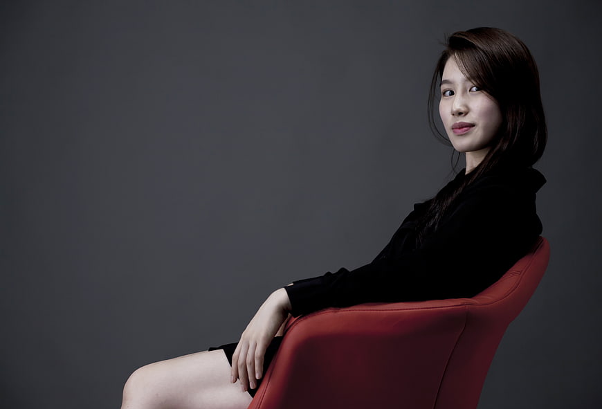 Studio Portrait of Woman in Black Seated on Red Chair