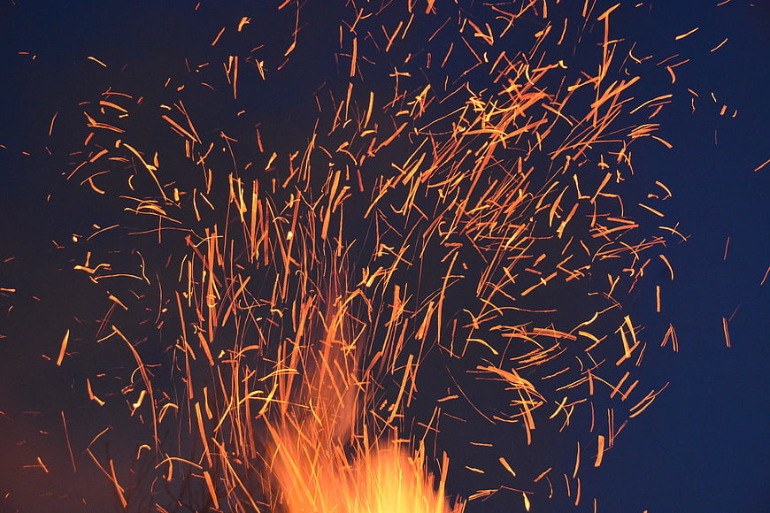 Dynamic Orange Sparks Flying Against Dark Blue Background
