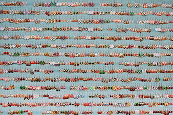 Colorful handmade earrings display on blue wall background