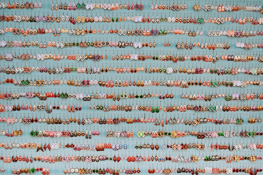 Colorful handmade earrings display on blue wall background