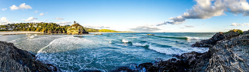 Panoramic coastal landscape featuring turquoise ocean waves and rocky shoreline