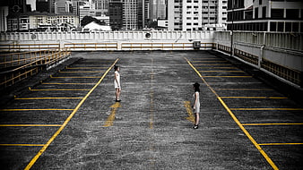 Two women standing in empty parking lot with yellow lines