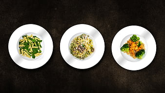 Three plated meals on white dishes against a dark textured background