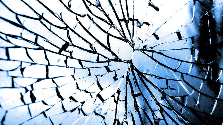 Close-up of shattered blue glass with radial cracks