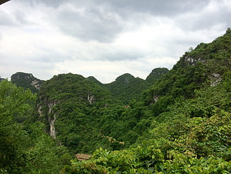 Lush green karst mountains under cloudy sky