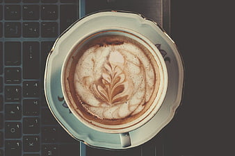 Top View Cappuccino with Latte Art on Laptop Keyboard