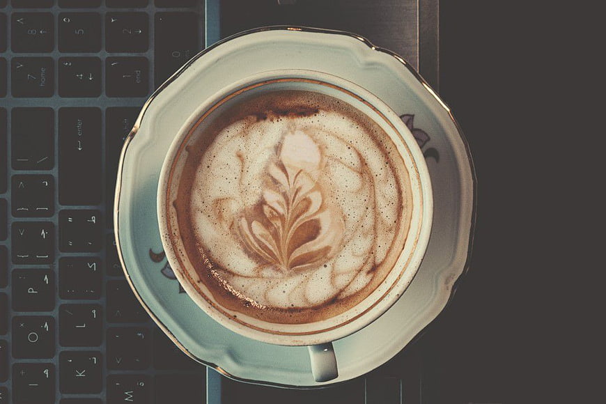Top View Cappuccino with Latte Art on Laptop Keyboard