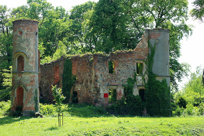 Abandoned brick castle ruins with ivy in summer forest