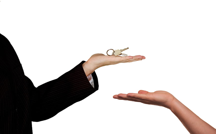 Real estate agent handing keys to buyer on white background