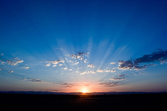 Dramatic Sunset with Sun Rays Over Silhouette Landscape