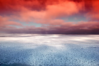 Dramatic red sunset over frozen icy lake with clouds