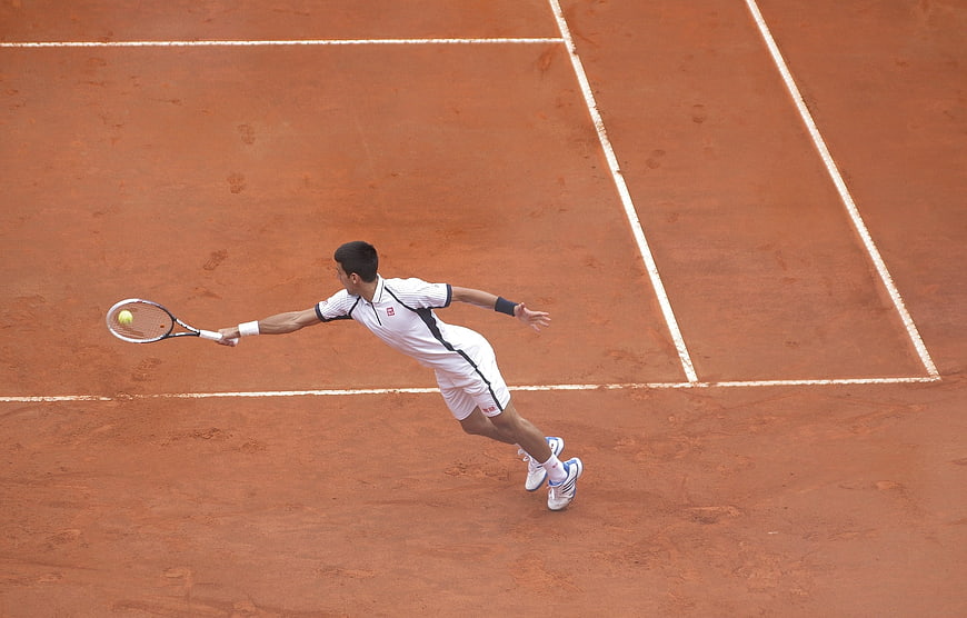 Tennis Player Stretching on Clay Court