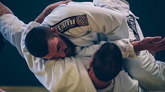 Two male athletes grappling in white Brazilian jiu-jitsu gis