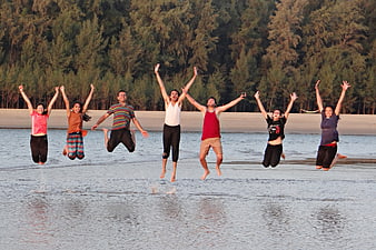 Group of young friends jumping joyfully on a beach shoreline