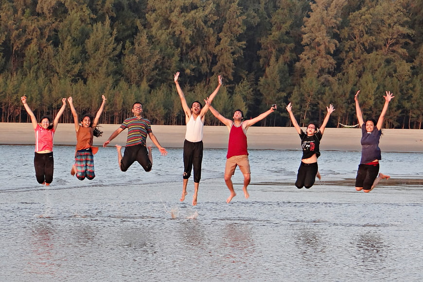 Group of young friends jumping joyfully on a beach shoreline
