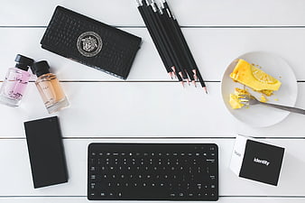 Flat lay workspace with keyboard, perfume, and cake