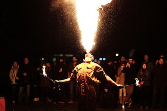 Fire Breather Performing at Night with Crowd