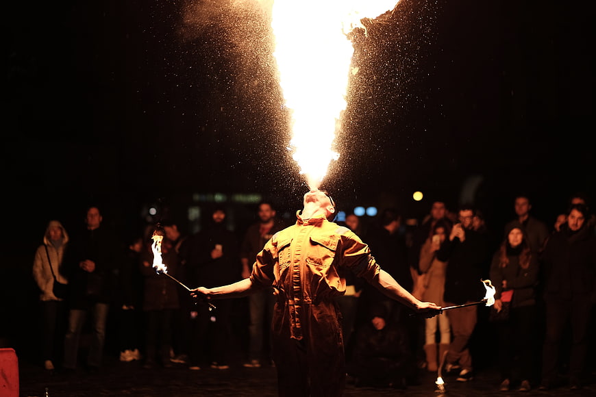 Fire Breather Performing at Night with Crowd