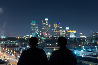Two Men Silhouetted Against Blurred Night City Skyline