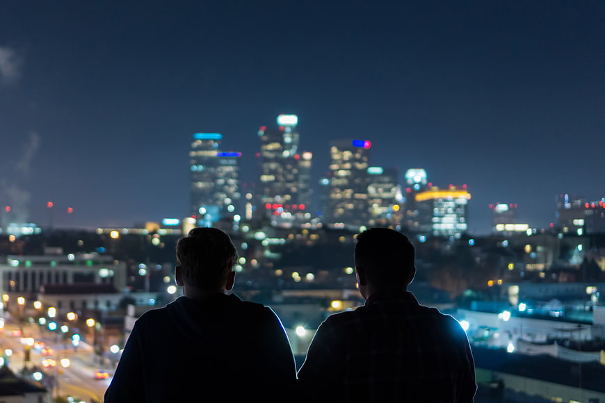 Two Men Silhouetted Against Blurred Night City Skyline
