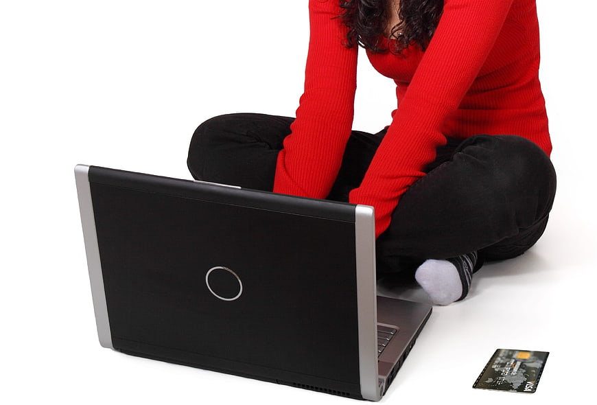 Woman in red top using laptop for online shopping with credit card