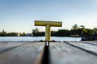 Close-up of yellow boat cleat on wooden dock by lake