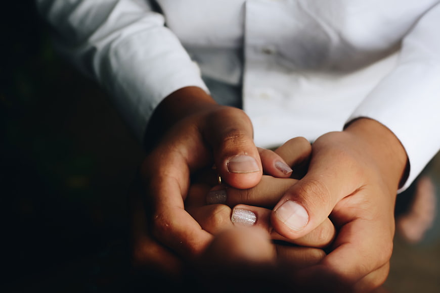 Close-up of couple holding hands with white shirt sleeves