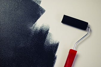 Paint roller with black paint on white wall background
