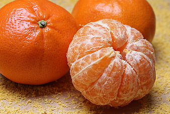 Fresh peeled mandarin orange with whole fruits on textured background