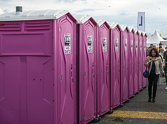 Row of purple portable toilets at an outdoor event