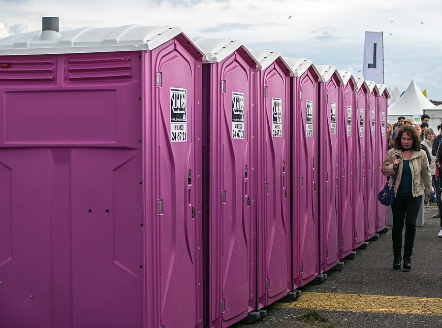 Row of purple portable toilets at an outdoor event