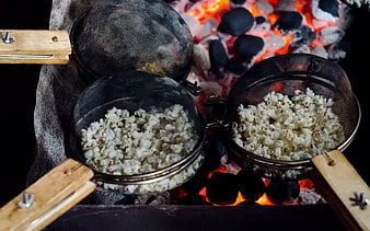 Popcorn cooking in mesh baskets over hot charcoal fire