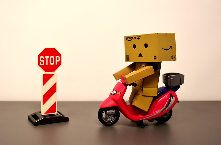 Danbo cardboard figure riding red scooter near stop sign