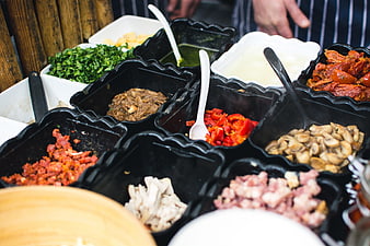 Fresh sandwich toppings and ingredients in black containers