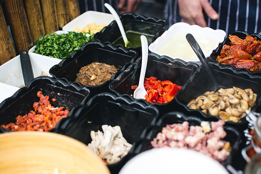 Fresh sandwich toppings and ingredients in black containers