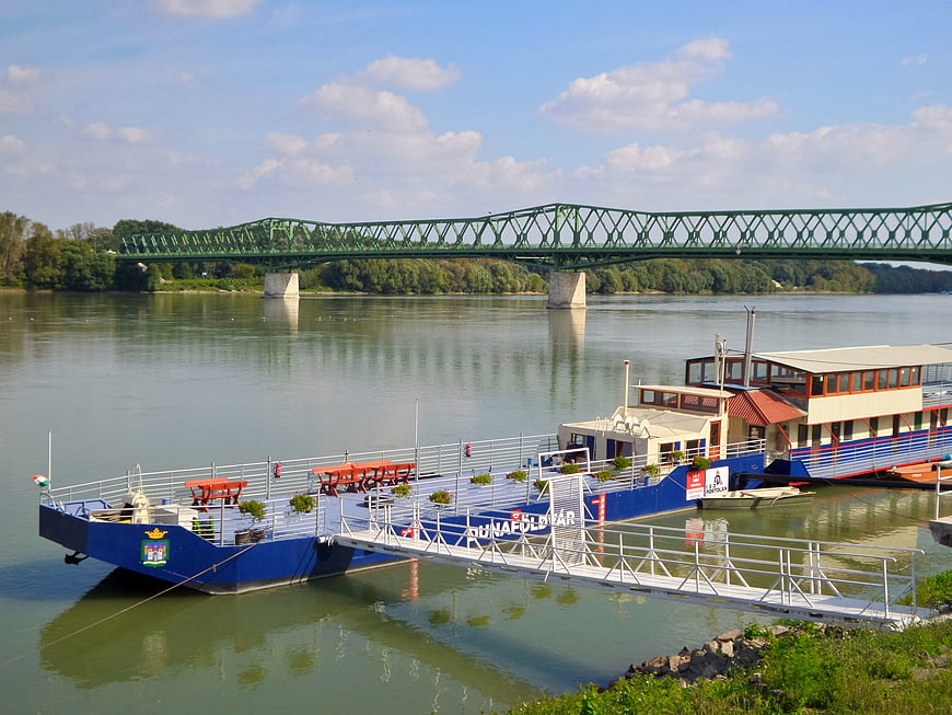 Blue river cruise boat docked near green bridge