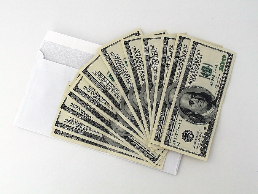 Stack of hundred dollar bills in white envelope