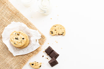 Flat lay of chocolate chip cookies and milk on white background