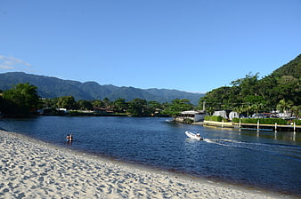 Sandy beach with river, mountains, and boat in Costa Rica