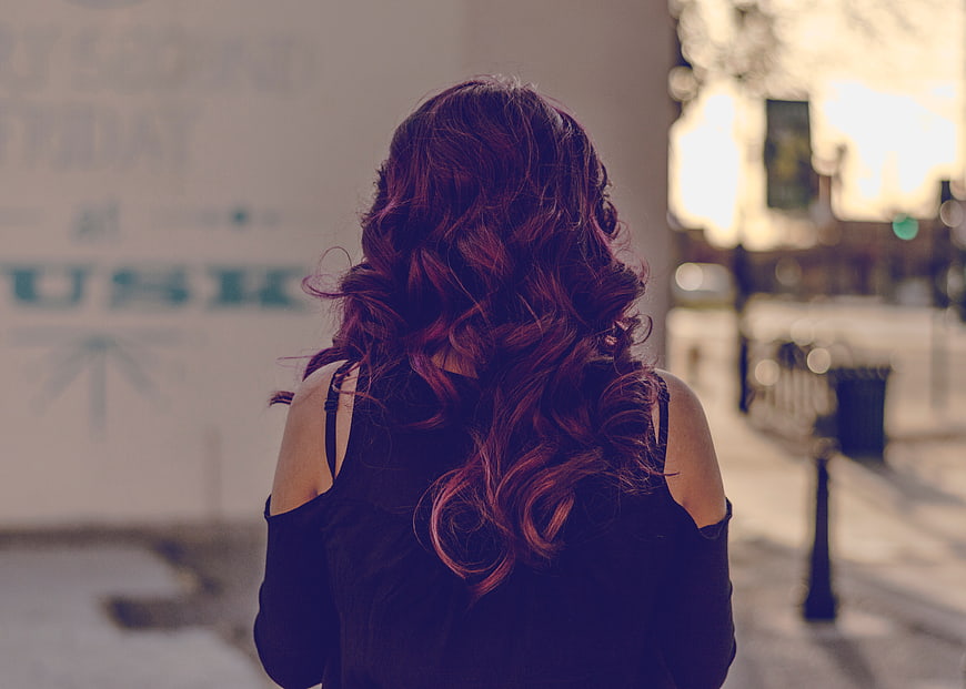 Woman with Red Curly Hair from Behind on City Street