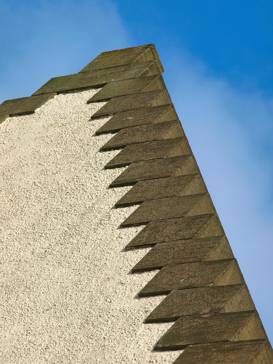 Low angle view of textured building corner against blue sky